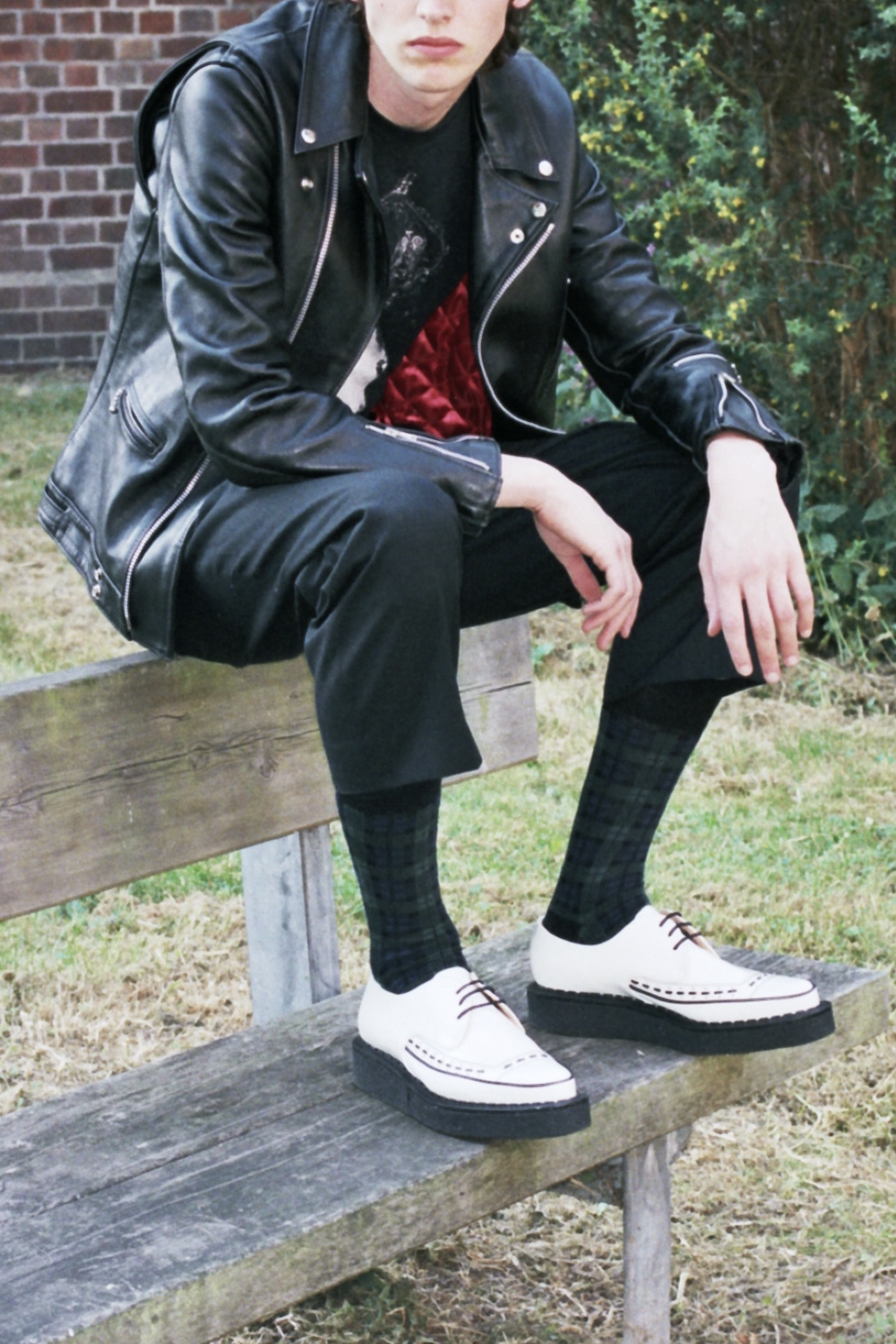 Punk sits on a park bench wearing white Diano Creepers